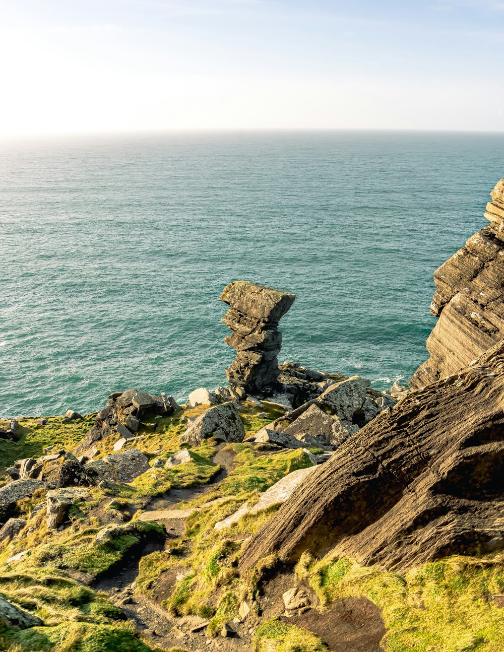 uma formação rochosa à beira de um penhasco com vista para o oceano