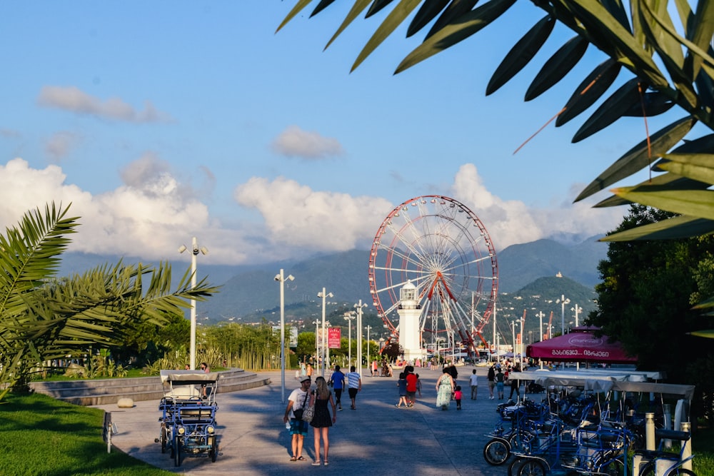 a group of people walking down a street next to a ferris wheel