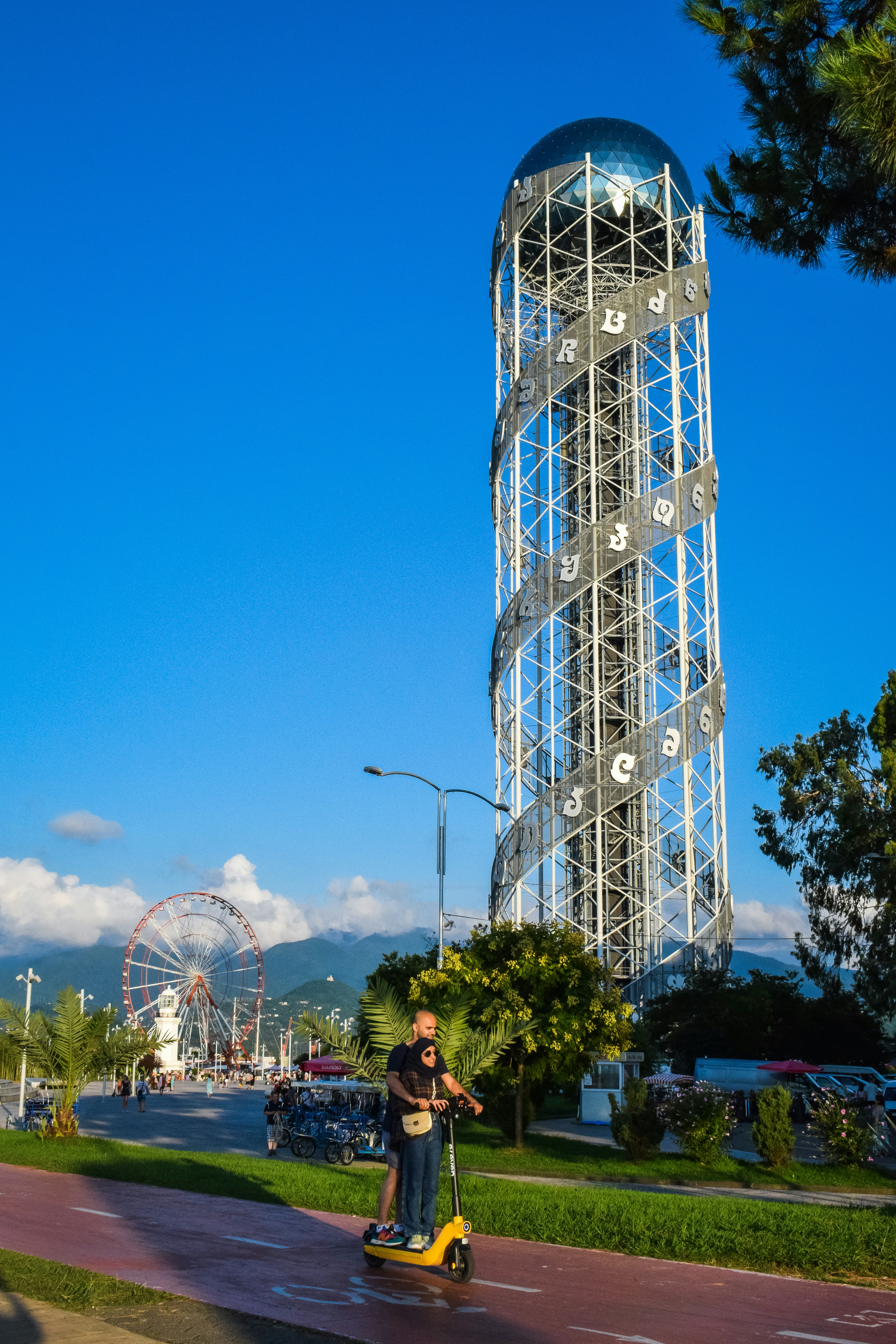 a man riding a scooter down a street next to a tall tower
