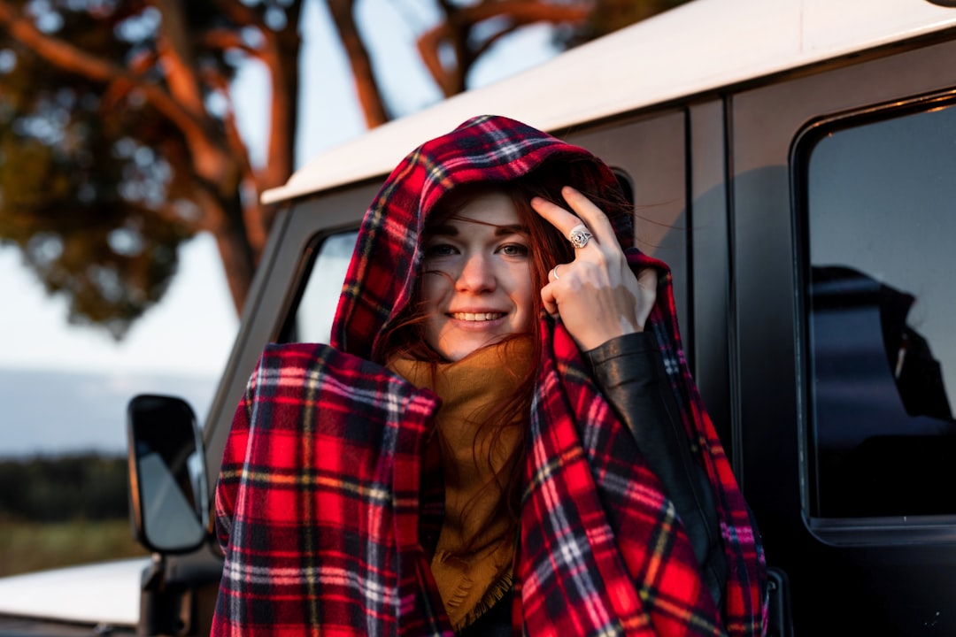 a woman in a red and black plaid blanket leaning out of a truck,