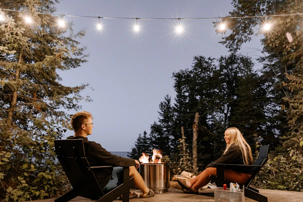 a man and a woman sitting at a table with a fire pit