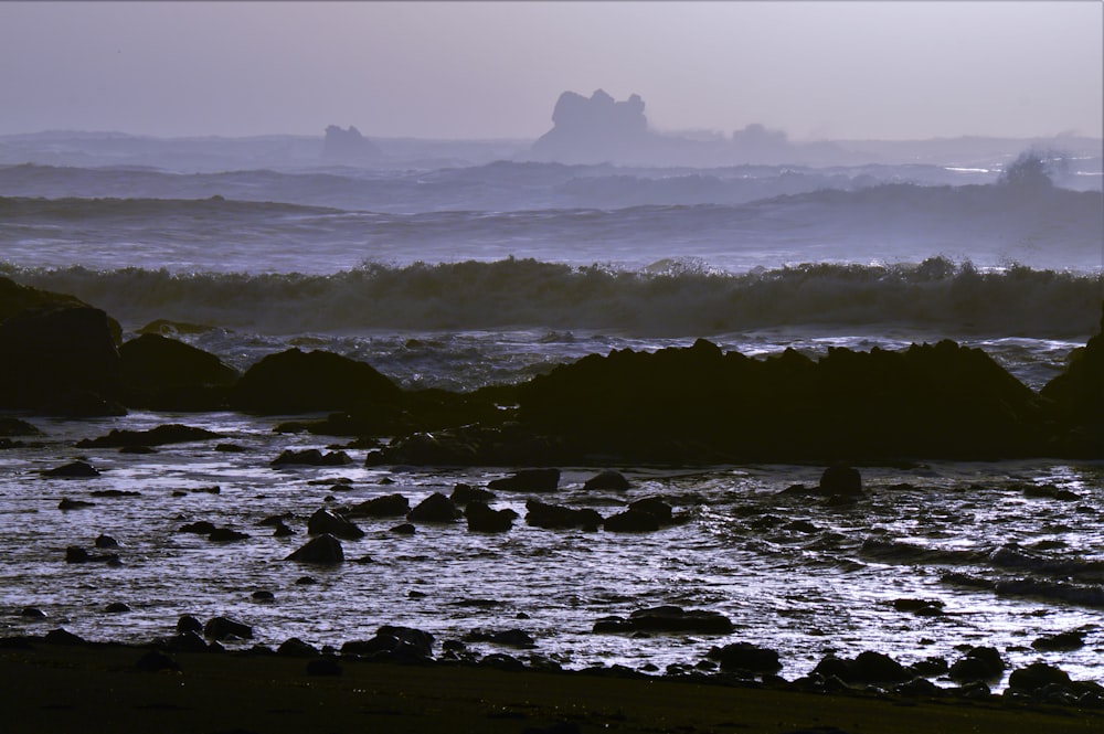 a large body of water with rocks in the foreground