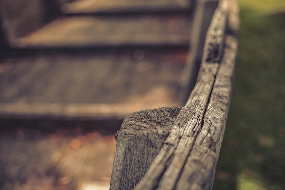 a close up of a wooden bench with grass in the background