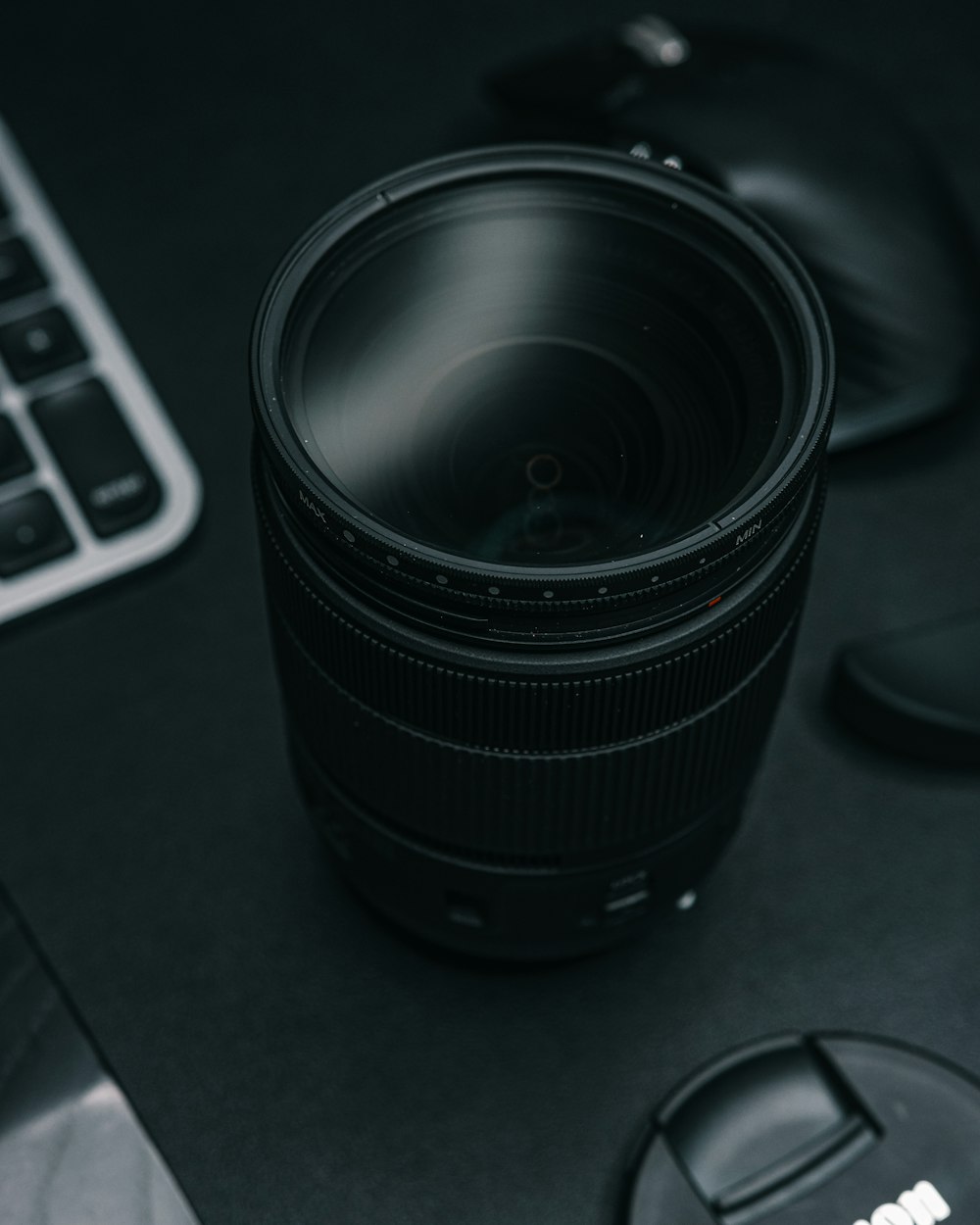 a camera lens sitting on top of a desk next to a keyboard