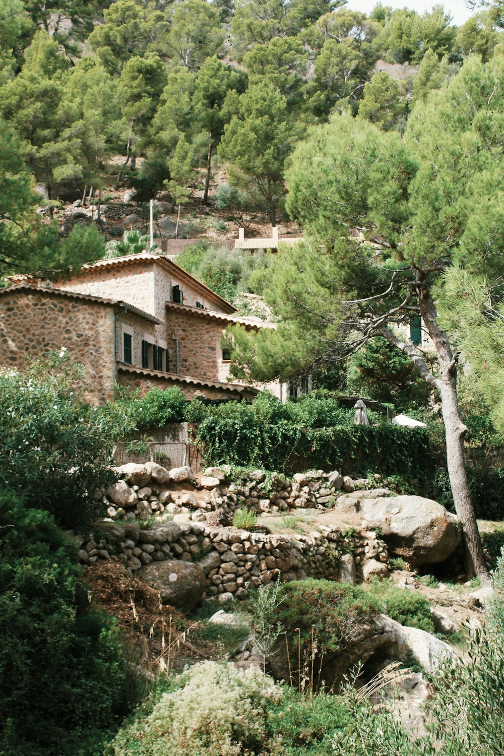 a stone house surrounded by trees and bushes