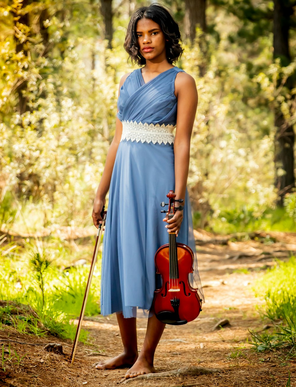 a woman in a blue dress holding a violin