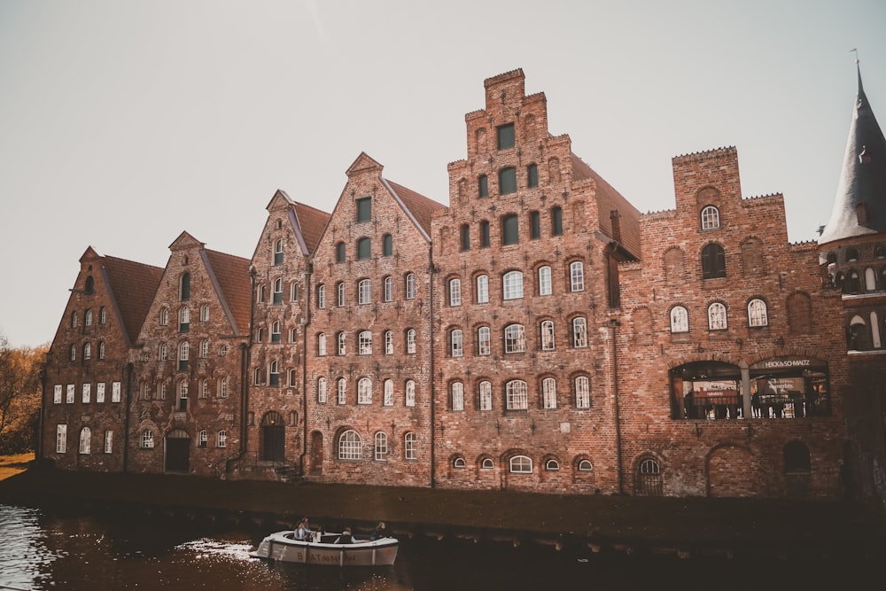 a boat traveling down a river next to a tall brick building