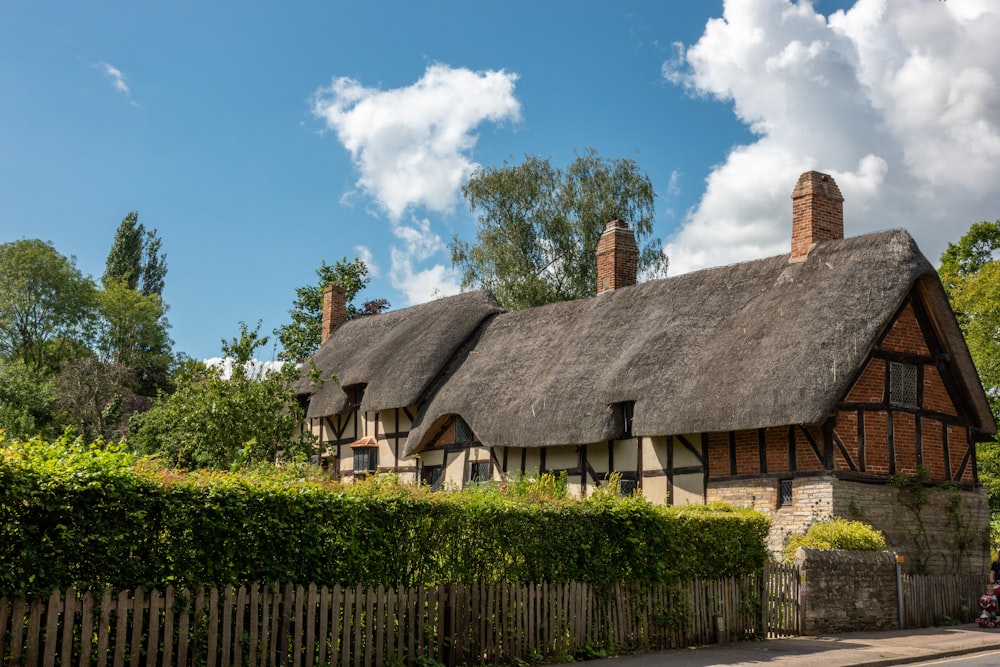 a house with a thatched roof next to a hedge
