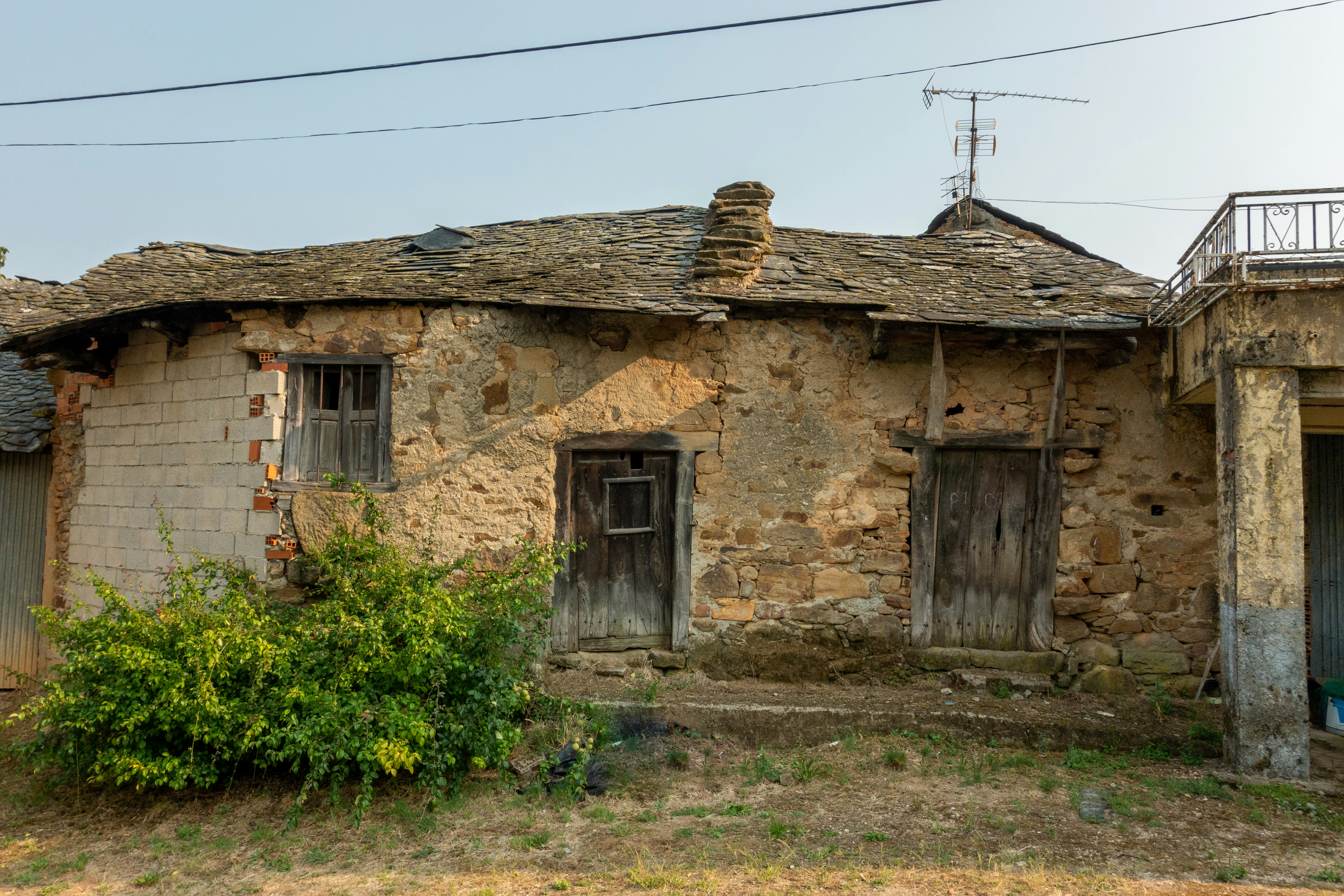 an old run down house with two doors and a roof