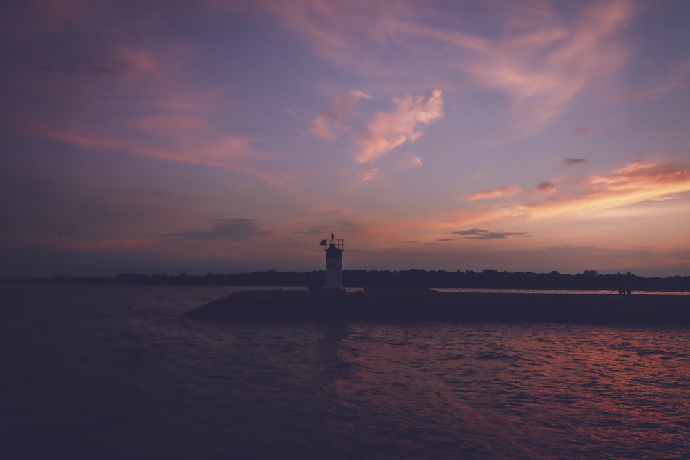 a lighthouse on a small island in the middle of a body of water