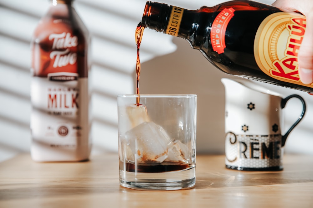 a person pouring a drink into a glass