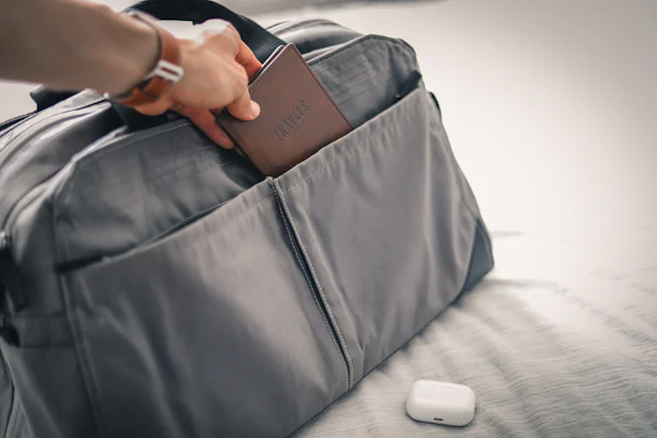 A person holding a wallet in a bag on a bed