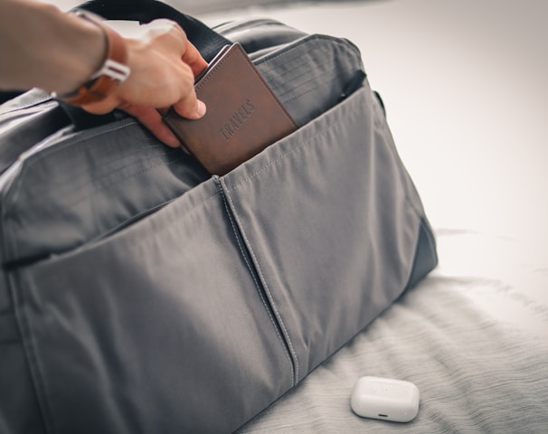 a person holding a wallet in a bag on a bed