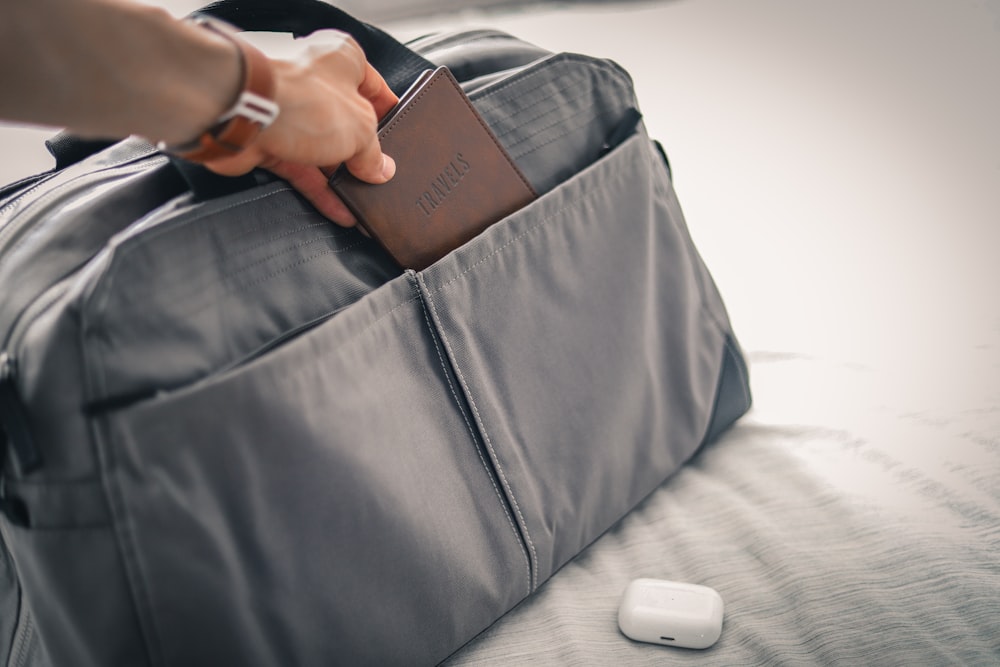a person holding a wallet in a bag on a bed