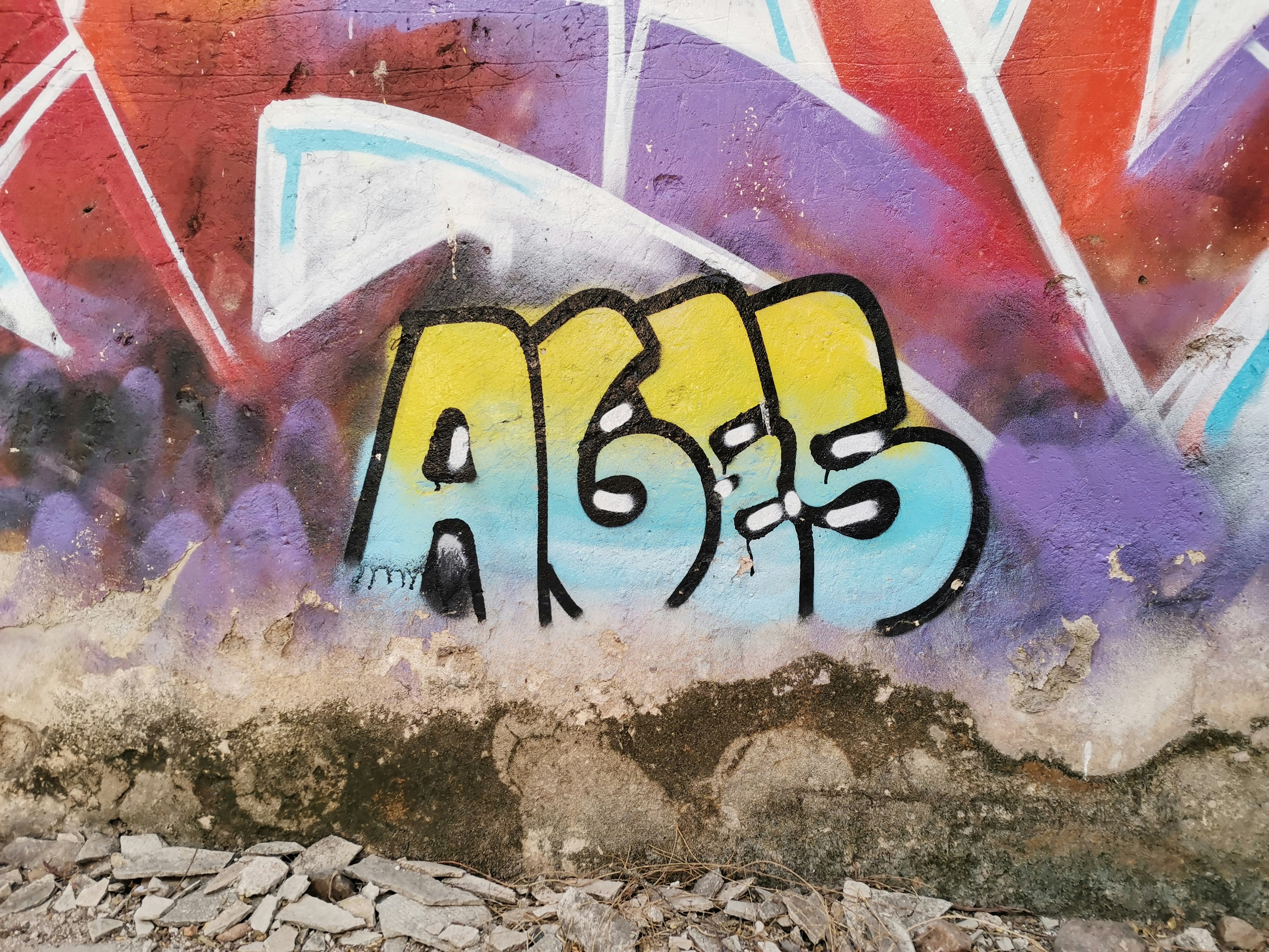 a wall covered in graffiti with a yellow and blue word