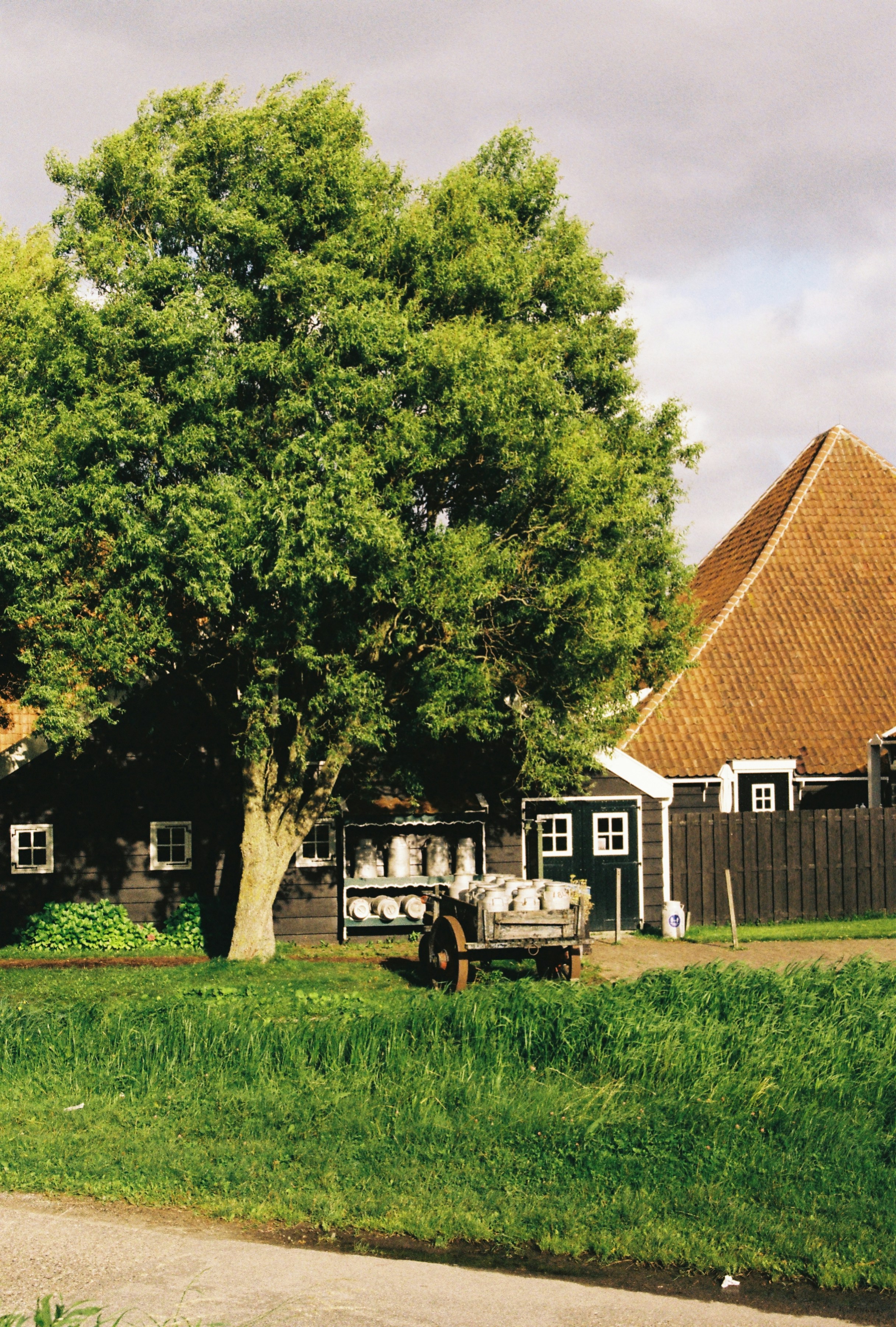 A wooden farm building with a cart of milk cans.