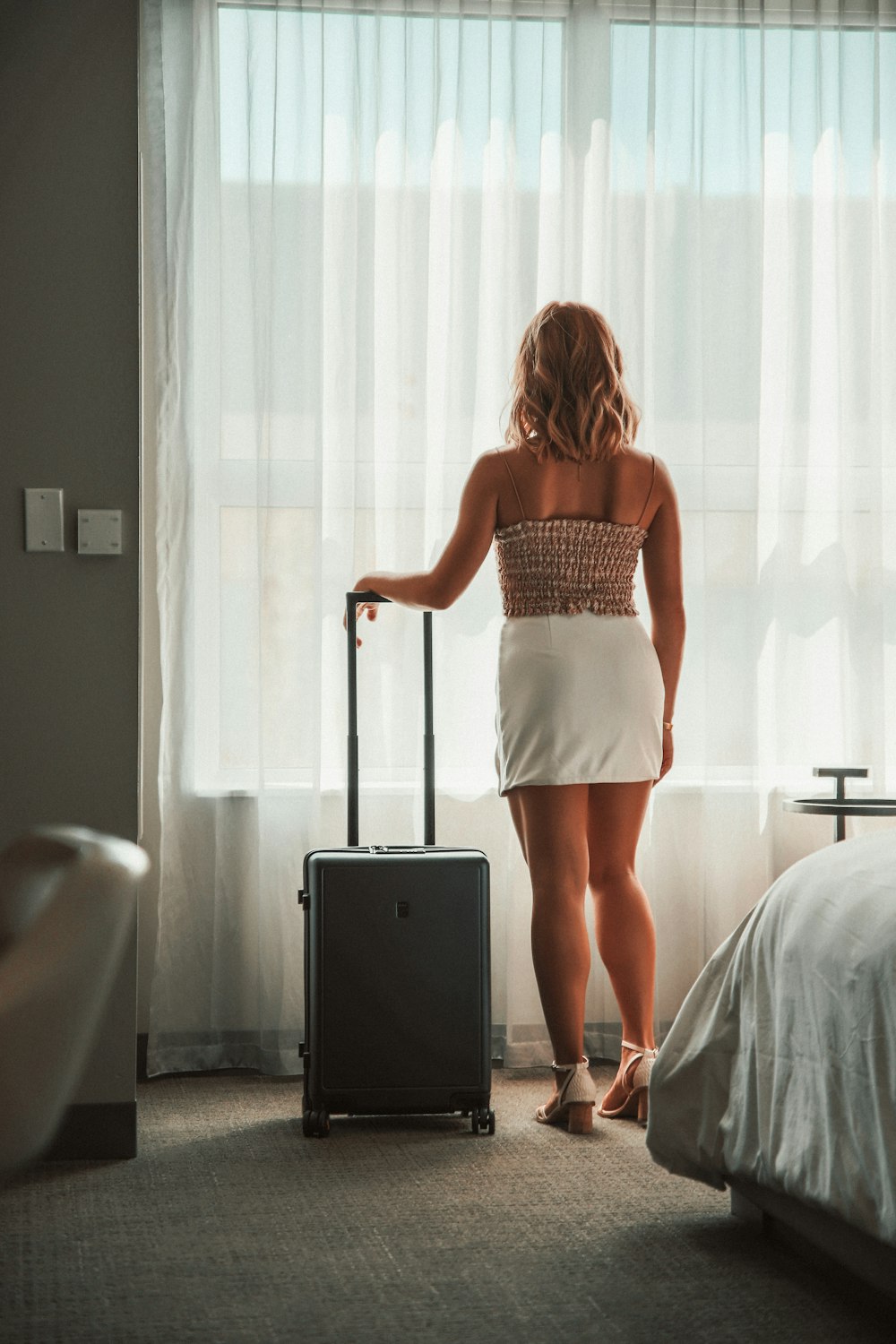a woman standing in a hotel room with a suitcase