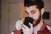 Close-up of a grumpy man’s gentle smile as he holds a vintage coffee mug.