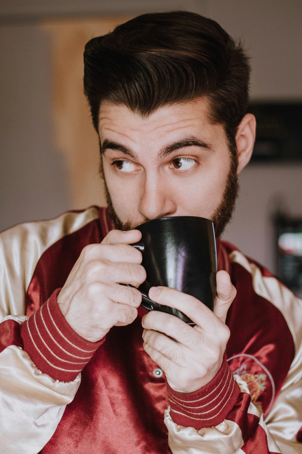 a man with a beard holding a coffee cup