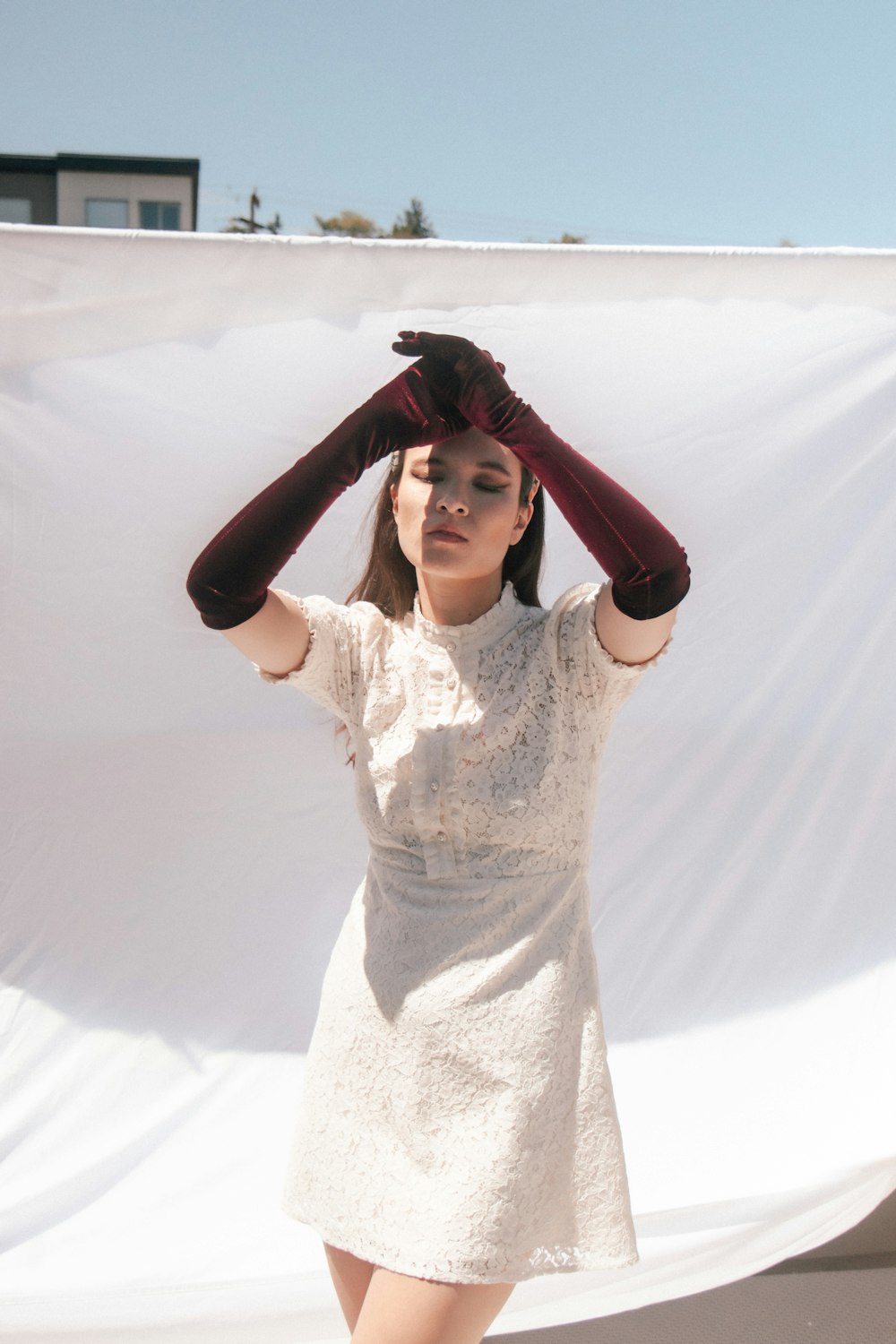 a woman in a white dress is holding her hands on her head