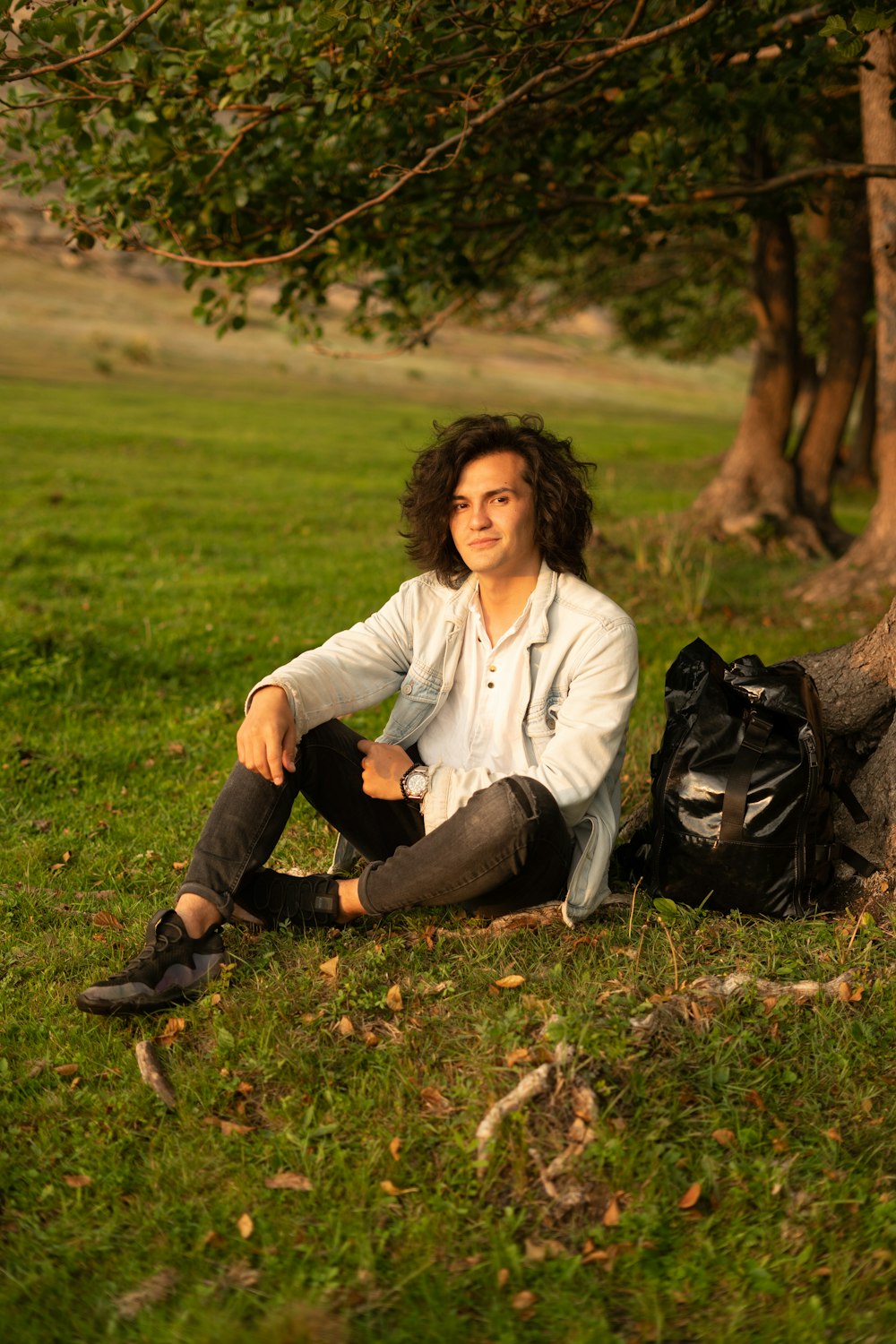 a man sitting in the grass next to a tree