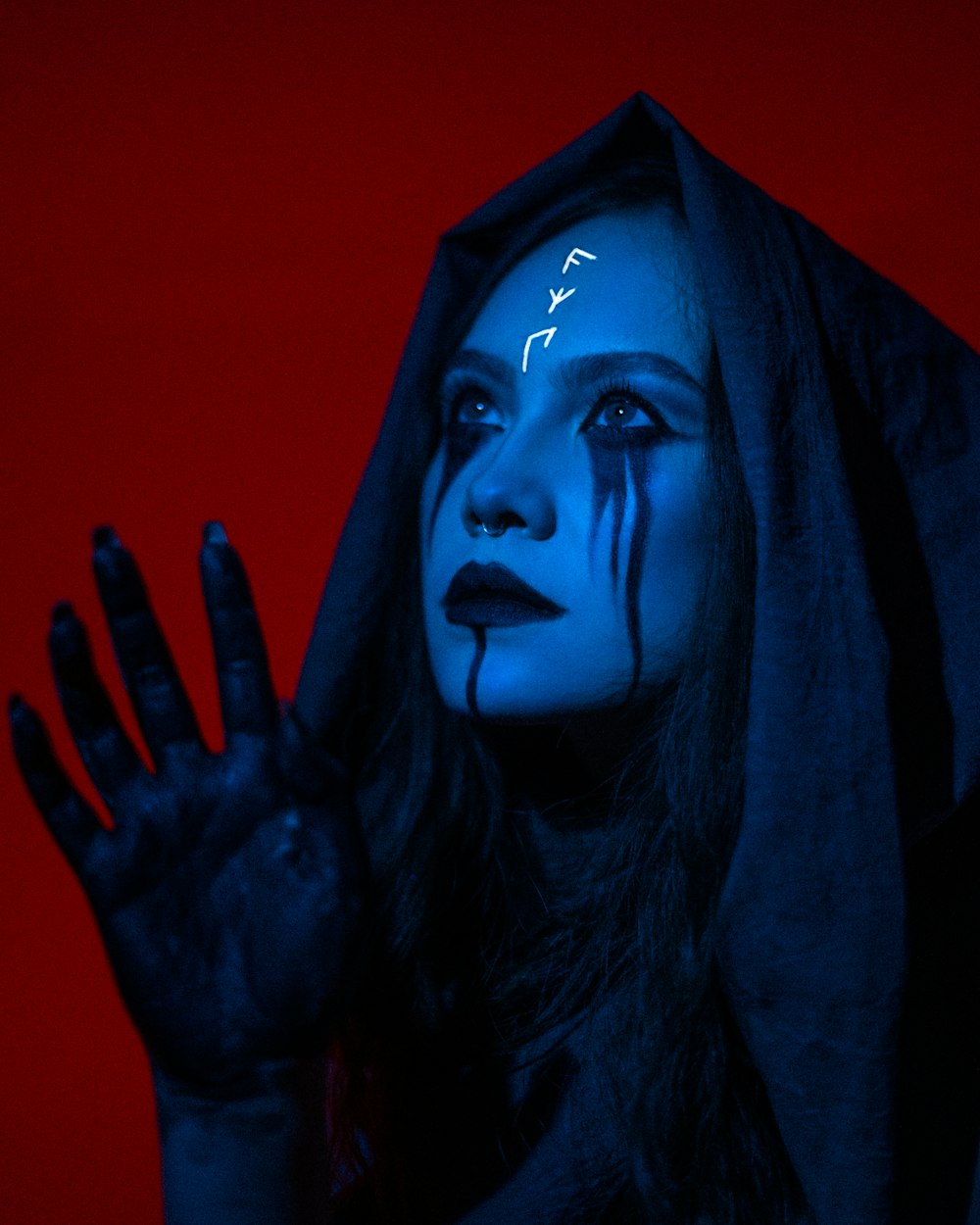 uma mulher com maquiagem azul segurando as mãos para cima