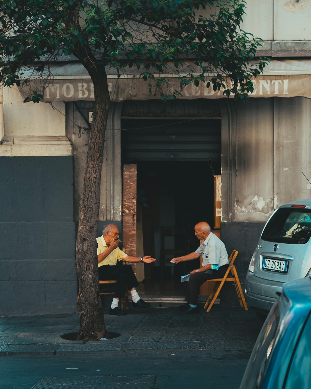 a couple of men sitting next to a tree