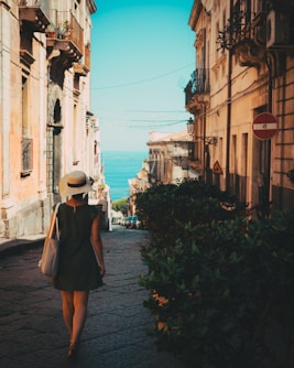 a woman in a hat walking down a street