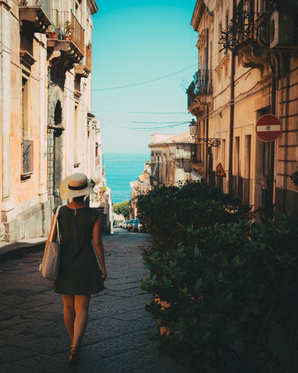 a woman in a hat walking down a street