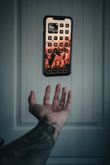 a hand holding a remote control in front of a wall