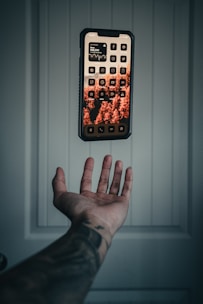 a hand holding a remote control in front of a wall