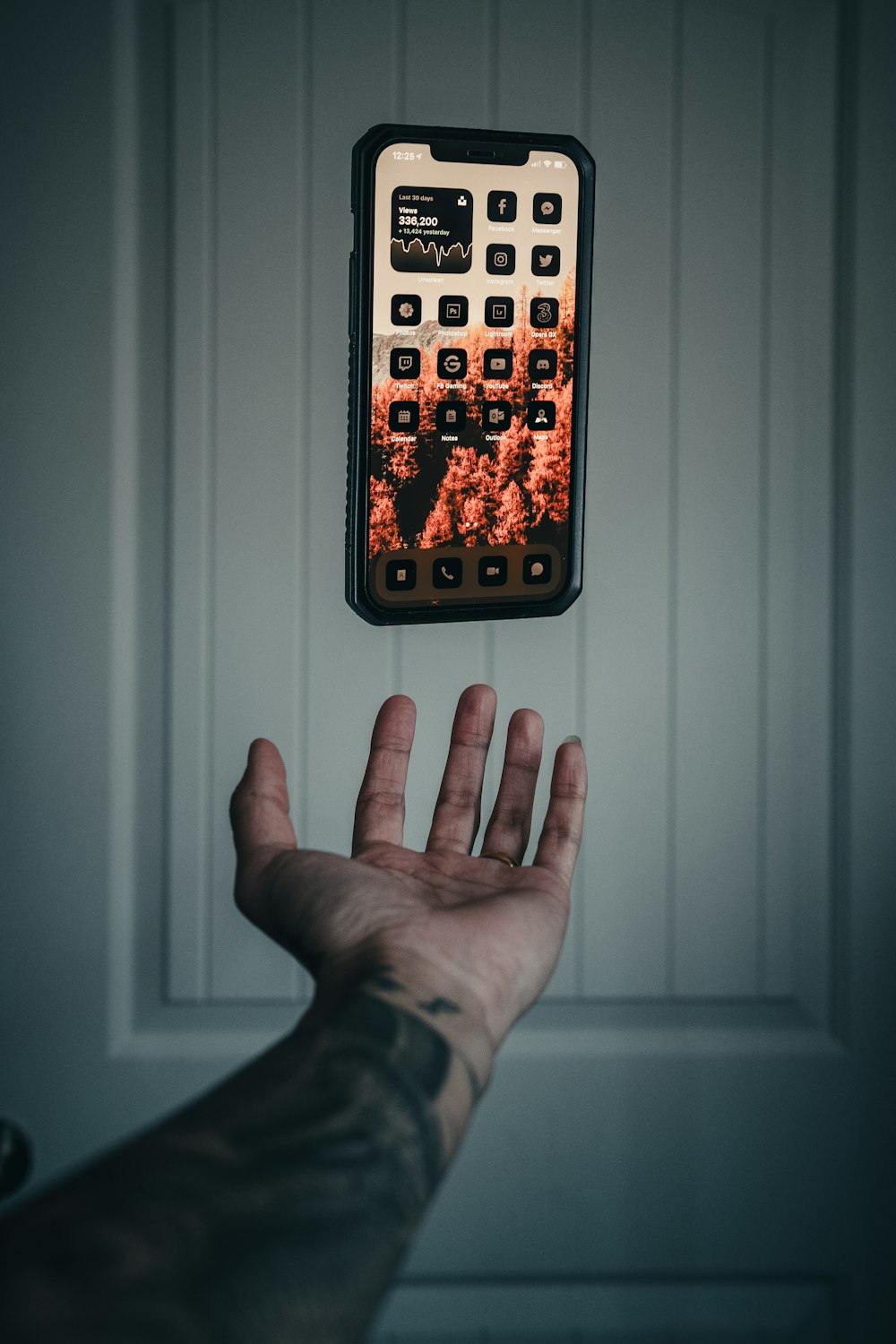 a hand holding a remote control in front of a wall