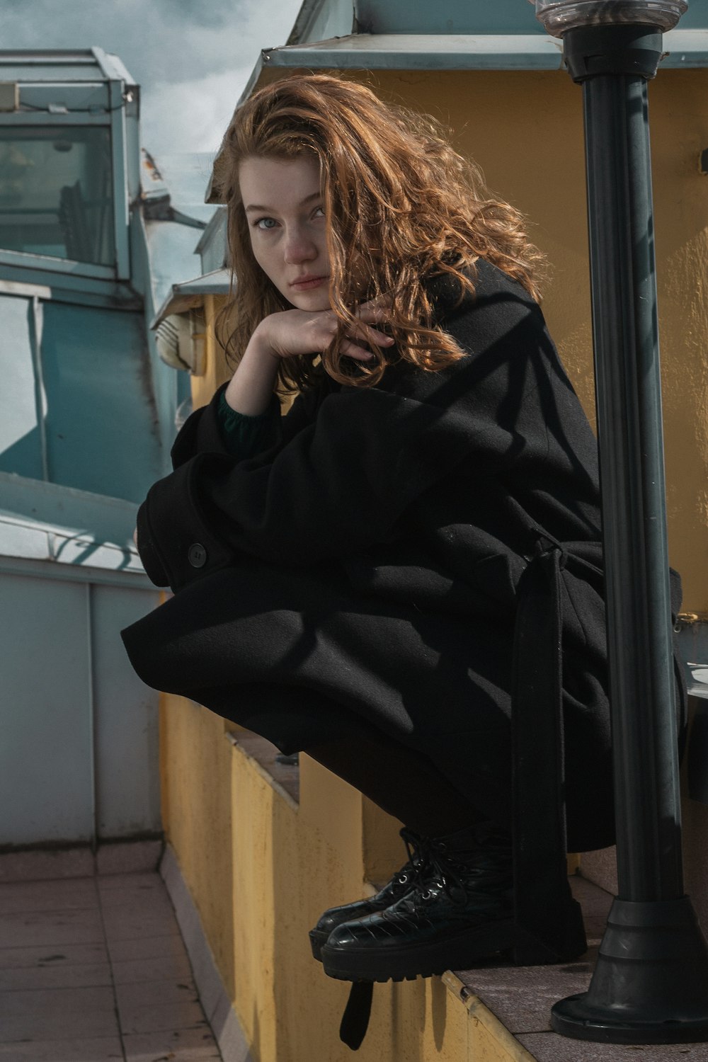 a woman sitting on a ledge next to a lamp post