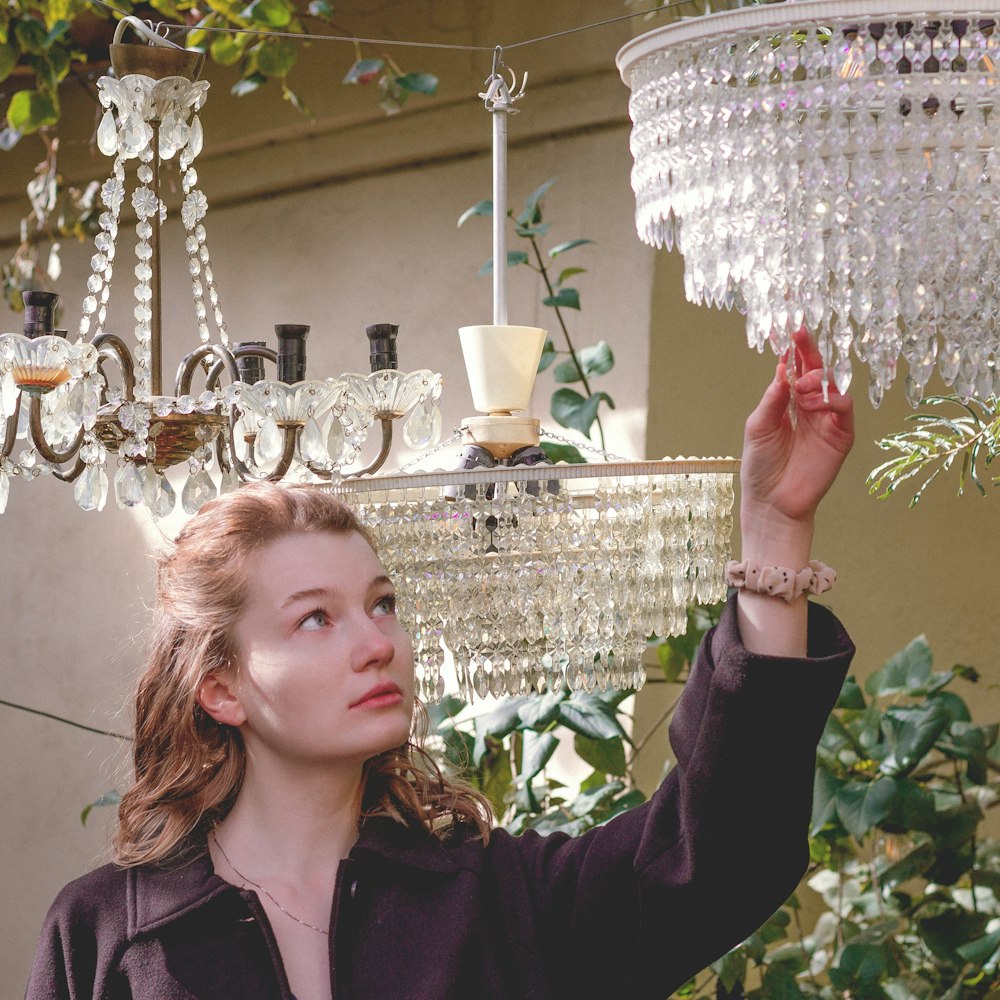 a woman holding a chandelier in her hand