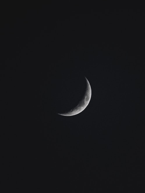 a half moon is seen in the dark sky