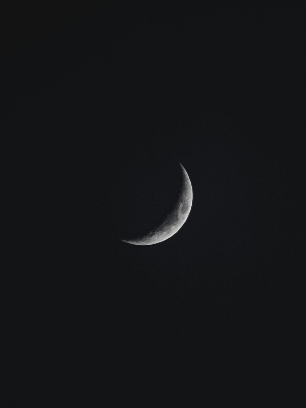 Une demi-lune est vue dans le ciel sombre