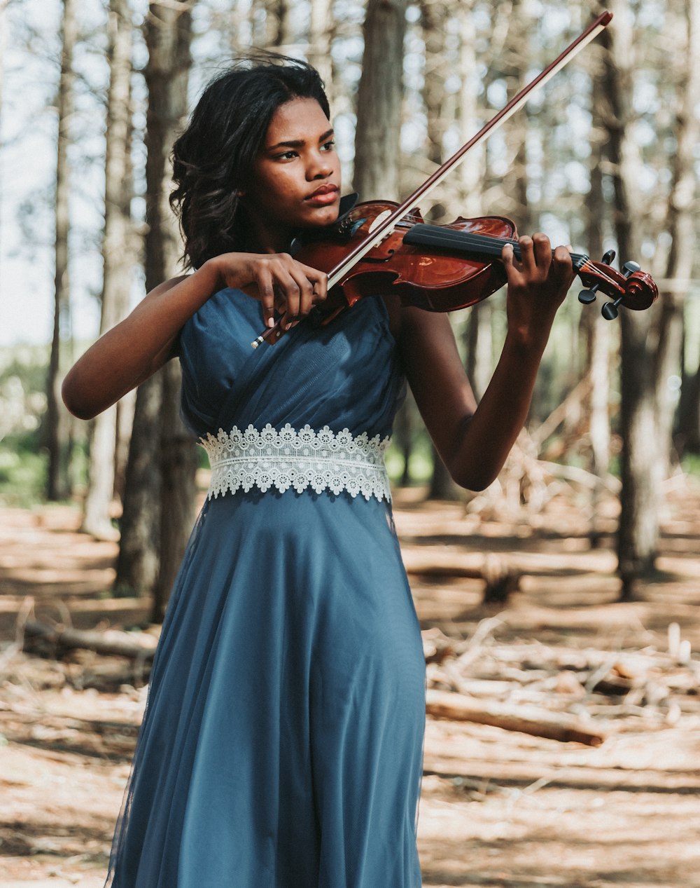 uma mulher em um vestido azul que joga um violino