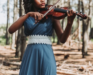 a woman in a blue dress playing a violin