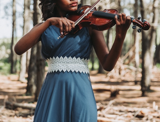 a woman in a blue dress playing a violin