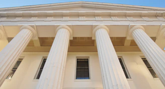 a tall white building with three large white pillars
