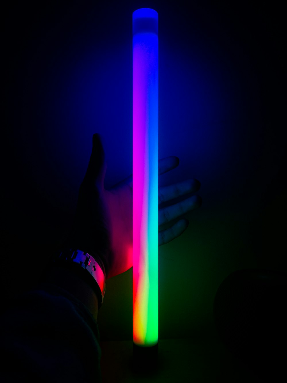 a person's hand next to a lit tube in the dark