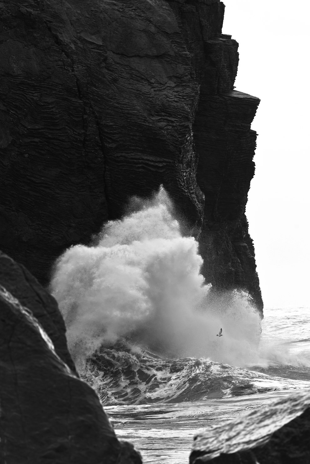 a large wave crashing into a rocky cliff