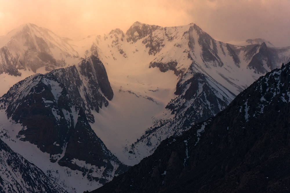 a mountain range covered in snow under a cloudy sky