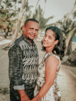 A sun-drenched candid of a couple laughing together on a sandy beach.