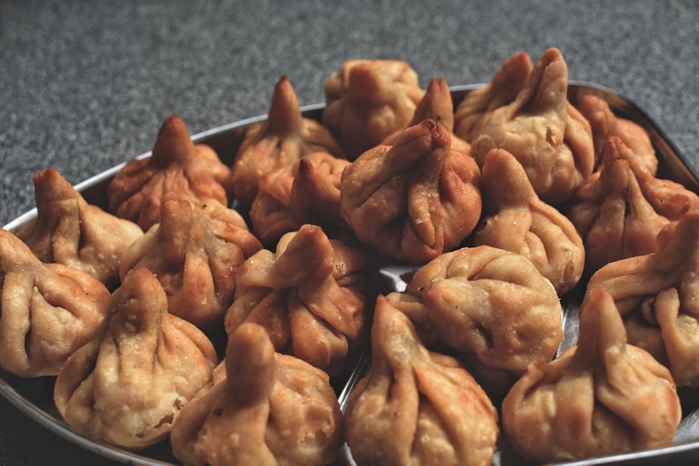 a metal tray filled with dumplings on top of a table