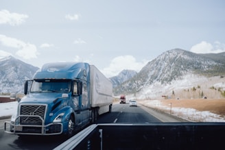 a blue semi truck driving down a mountain road