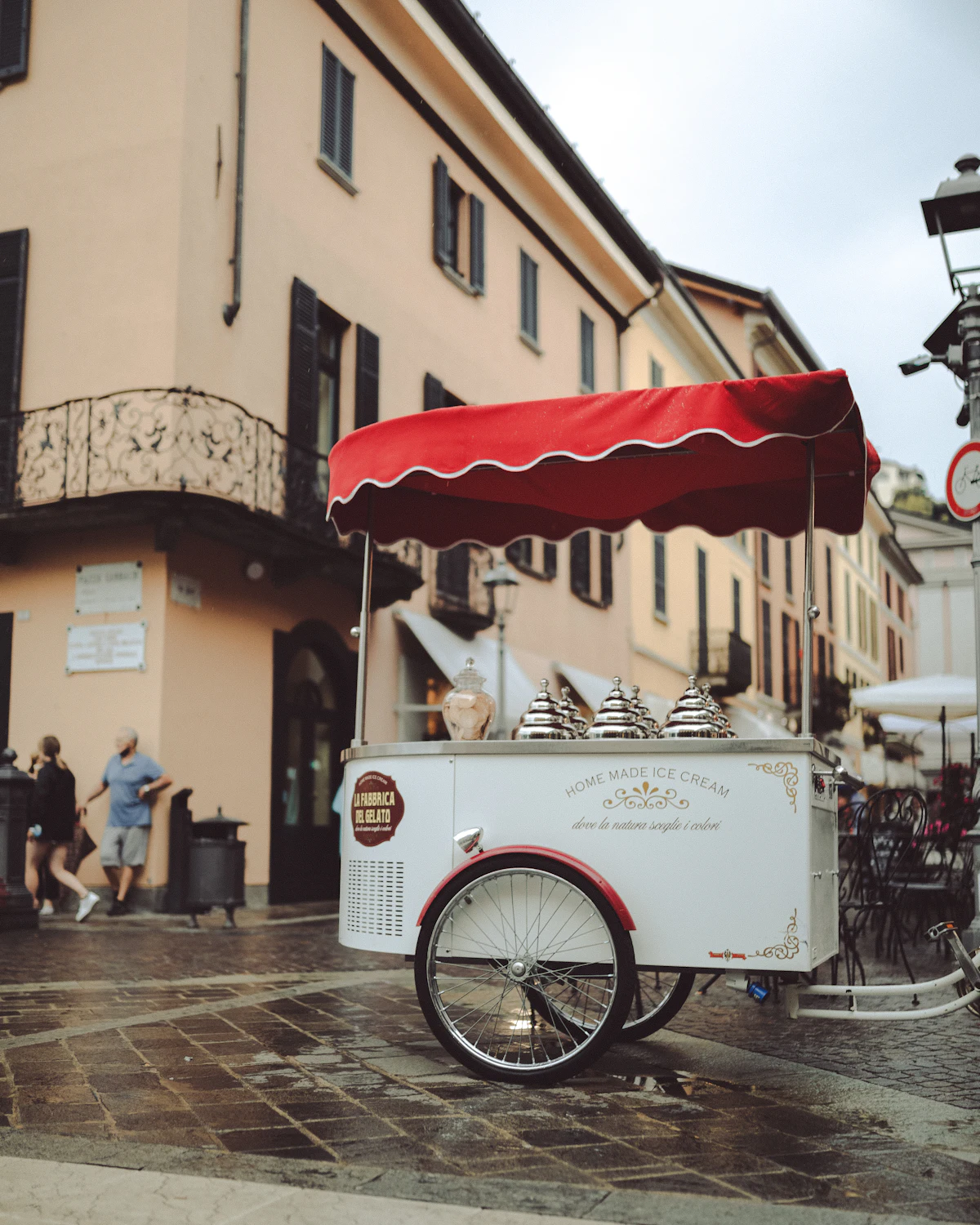 A small ice cream vending cart parked at the side of a street