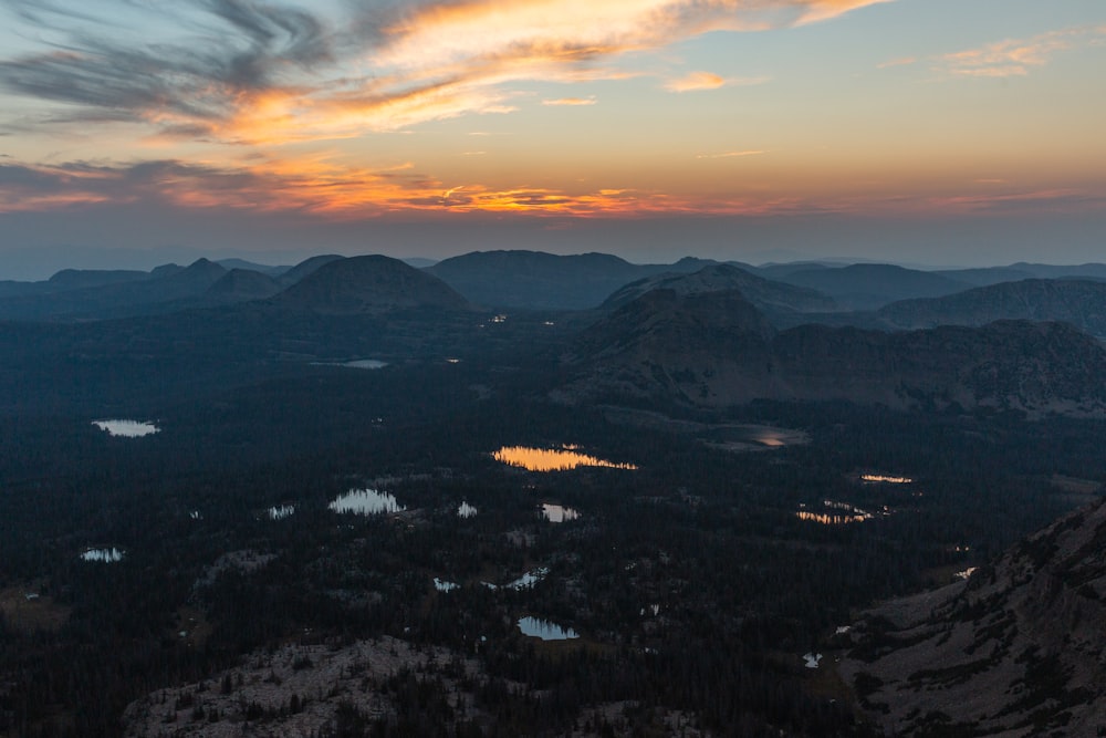 a beautiful sunset over a mountain range with a lake in the foreground