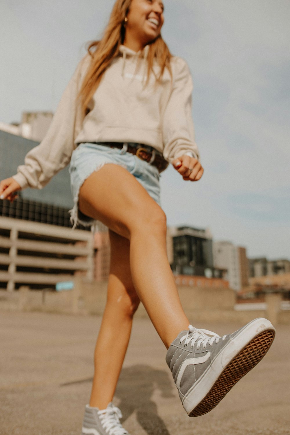 a woman in a white shirt and blue shorts is riding a skateboard