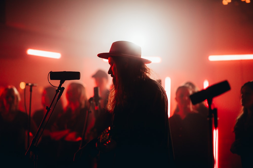 a man in a hat standing in front of a microphone